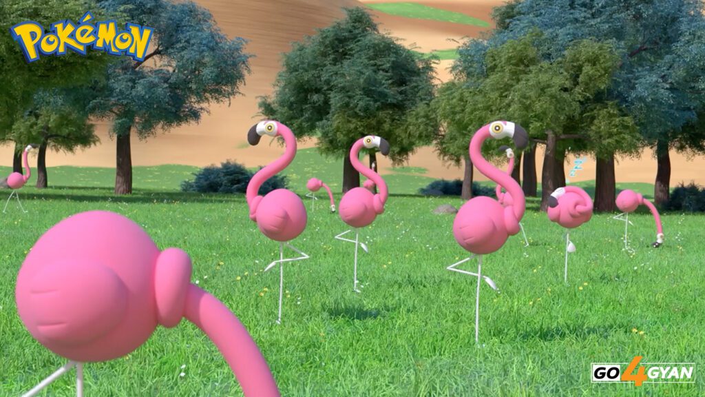 A simple illustration showing a Flamigo standing in knee-deep water near a grassy shoreline with a lighthouse visible in the background.